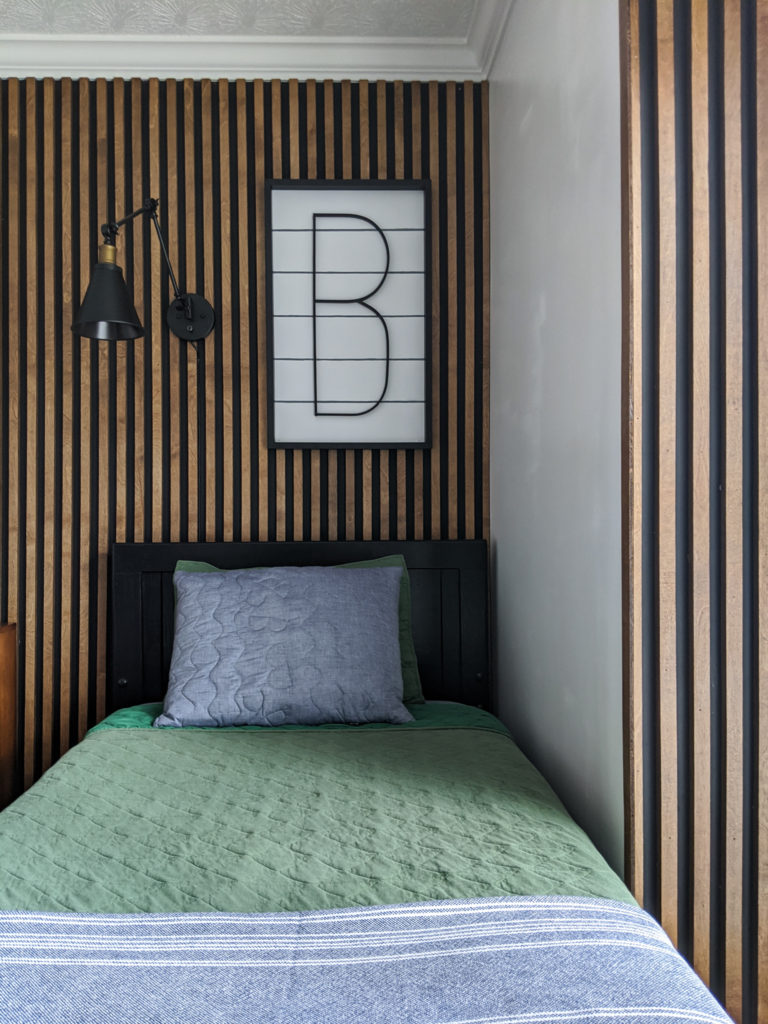Boys-bed-with-slat-wall-faux-shiplap-sign-and-sconce-over-bed