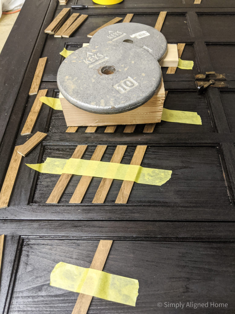 Hold-wood-slats-in-place-with-painters-tape-and-weights