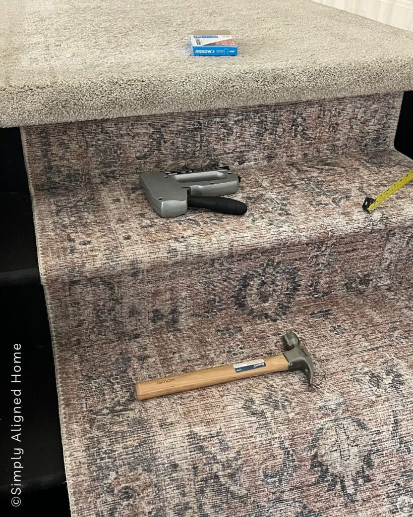 Using a stapler manually to install carpet on stairs. 